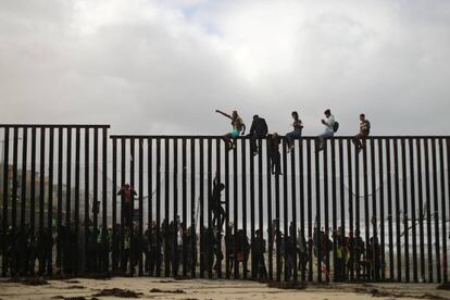 Migrantes encaramados a la valla que separa México de EE UU en San Diego (California), el 29 de abril.