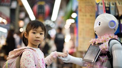 A little girl holds a robot’s hands in a market in Osaka, Japan.