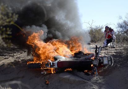 El piloto portugu&eacute;s Paulo Goncalves llora desconsoladamente mientras su Honda arde durante la etapa de hoy del Rally Dakar. 