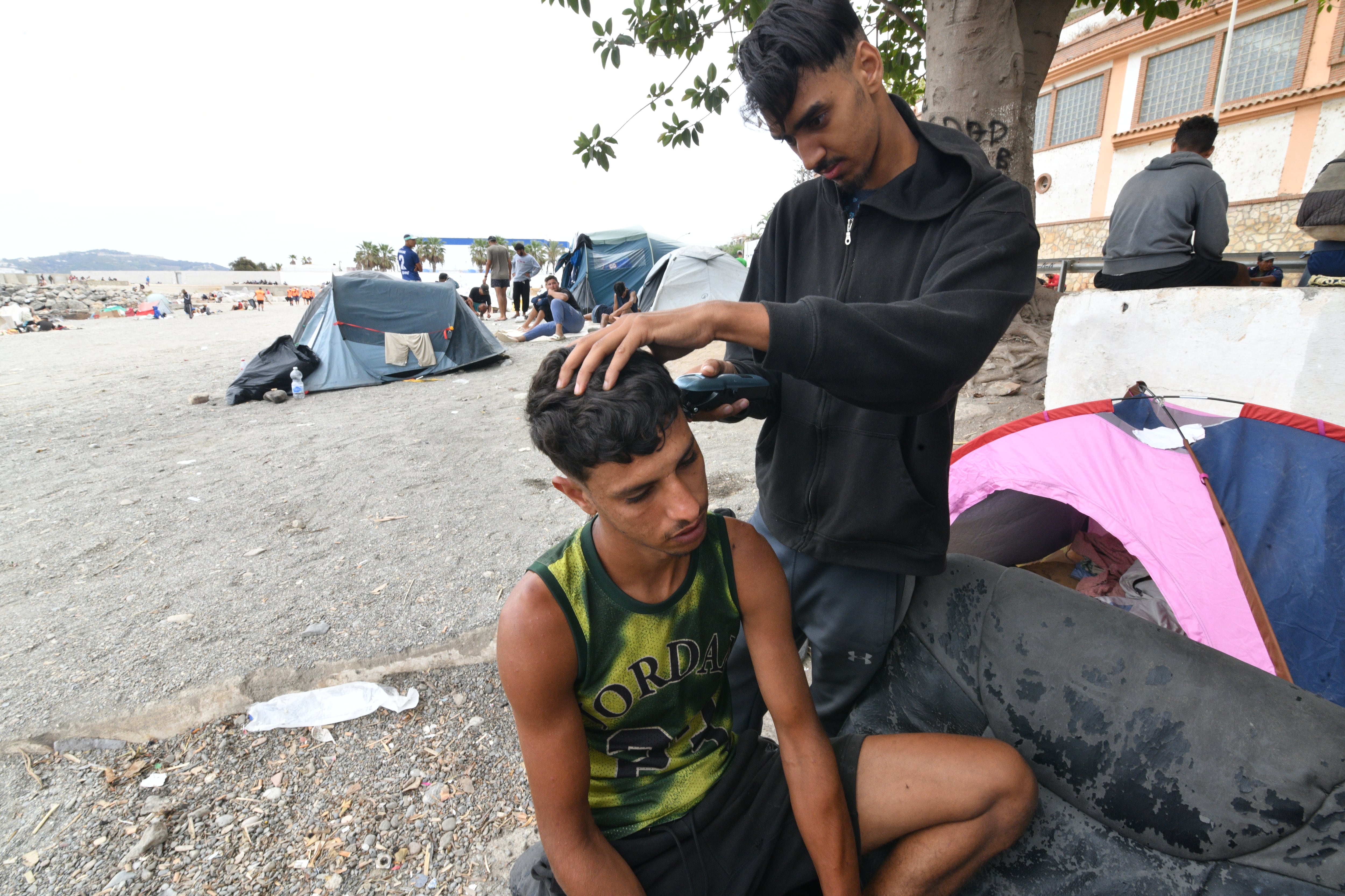 Un joven le corta el pelo a otro en la playa de El Trampolín, este domingo. 