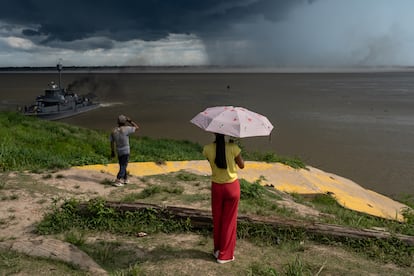 Dos personas miran una tormenta caer en la orilla opuesta del río Amazonas, luego de varios meses de sequía, en Puerto Nariño, el 15 de octubre de 2024.