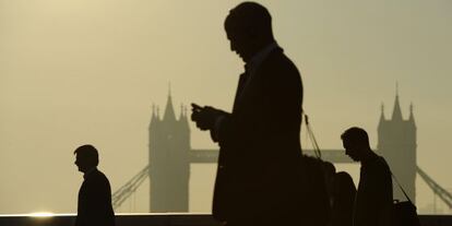 Unos directivos manejan sus m&oacute;viles en Londres. 