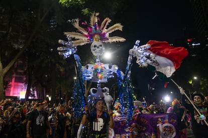 Una mujer carga sobre sus hombros la efigie de una calavera con un penacho, durante el desfile de este domingo.