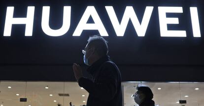 Dos personas pasan junto a una tienda de Huawei en Pekín.