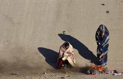 Migrantes se calientan cerca de una fogata a orillas del río Bravo en Ciudad Juárez, el viernes pasado.