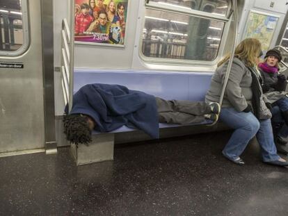 Un hombre sin hogar duerme en el metro de Nueva York.