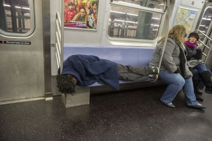 Un hombre sin hogar duerme en el metro de Nueva York.