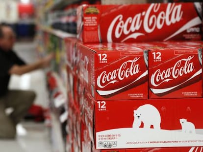 Un hombre organiza cajas de Coca-Cola en un supermercado