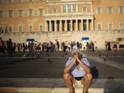 Un ciudadano se sienta pensativo frente al Parlamento griego.