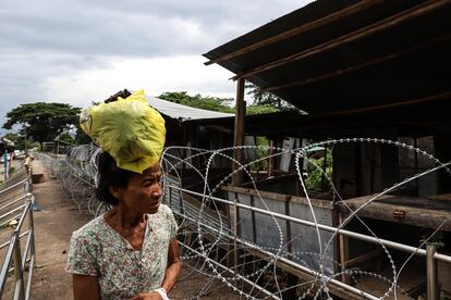 Una mujer camina cerca de un campamento improvisado donde viven refugiados de Myanmar, cerca del Puente de la Amistad entre Tailandia y Myanmar. El lugar está delimitado por un alambre de espino.
