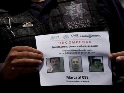 Un policía muestra el letrero de "Se Busca" de El Chapo.