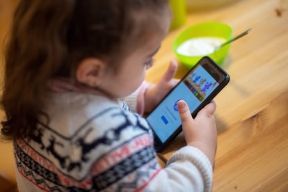 Una niña juega con un teléfono móvil.