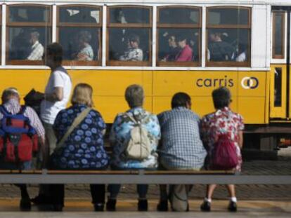 Un grupo de turistas ve pasar un tranvía en Lisboa.