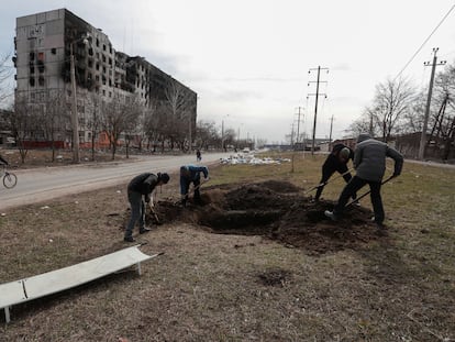 Un grupo de hombres cava una fosa para enterrar a víctimas mortales del ataque a Mariupol, el domingo.