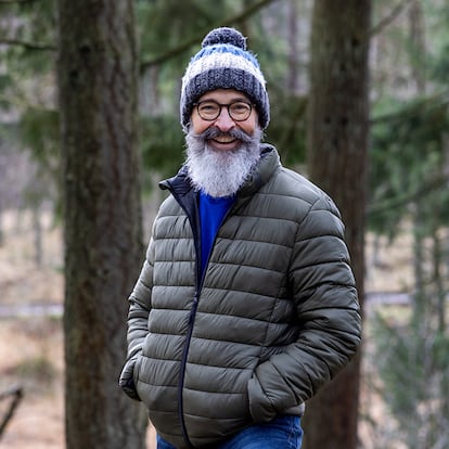 Un hombre con un abrigo en el campo entre árboles.