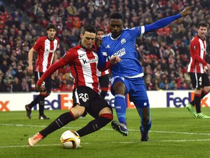 El defensa camerunés del Olympique de Marsella, Nicolas Nkoulou pelea un balón con el delantero del Athletic Club de Bilbao Aritz Aduriz en el partido de vuelta de octavos de final de la Europa League celebrado en San Mamés.