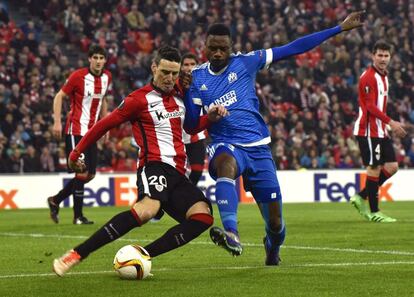 El defensa camerunés del Olympique de Marsella, Nicolas Nkoulou pelea un balón con el delantero del Athletic Club de Bilbao Aritz Aduriz en el partido de vuelta de octavos de final de la Europa League celebrado en San Mamés.