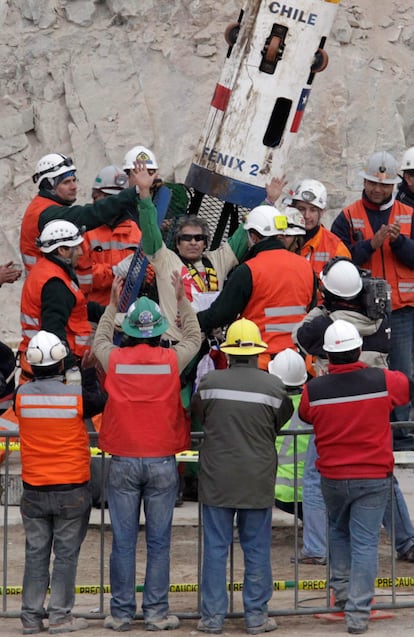 Mario Gómez, de 63 años, saluda a su llegada a la superficie dentro de la cápsula Fénix, en el noveno viaje de rescate. El minero, casado y con cuatro hijos, padece silicosis e hipertensión, por lo que representaba "el desafío más serio" para el equipo médico.