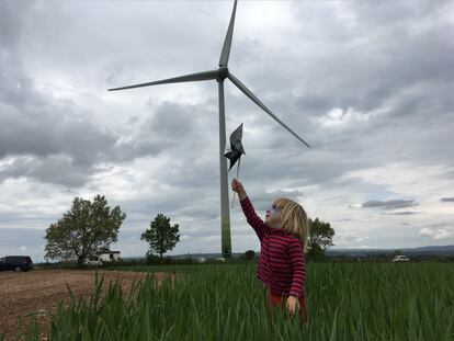 Una niña juega junto al aerogenerador instalado por los socios de Viure de l'aire del cel en Pujalt (Barcelona).