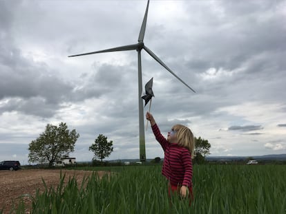 Una niña juega junto al aerogenerador instalado por los socios de Viure de l'aire del cel en Pujalt (Barcelona).