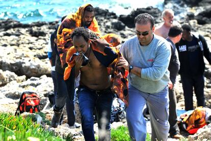 Los Guardacostas griegos han rescatado a 83 personas de las aguas en la zona de Zephiros, donde el barco, que presumiblemente partió de Turquía, chocó contra unas rocas y se partió. En la imagen, una persona ayuda a uno de los inmigrantes rescatados en la isla griega de Rodas.