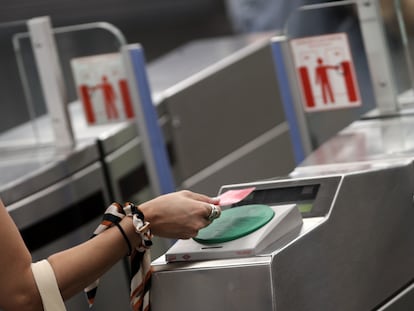 Una mujer pasa su tarjeta de transporte público por el torno del Metro Plaza de España, en Madrid, el 6 de julio de 2020.