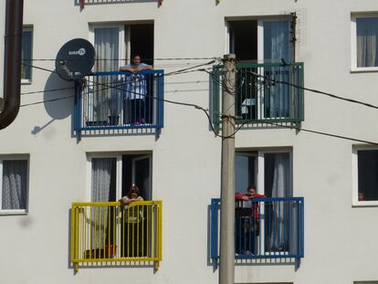 Tres mujeres se asoman al balcón para observar la inauguración de la entrega de llaves de ocho viviendas del proyecto Roma Action, en la localidad de Kakanj, en Bosnia.