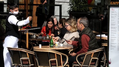 Una camarera atiende a varios clientes en una terraza de un bar de Madrid.