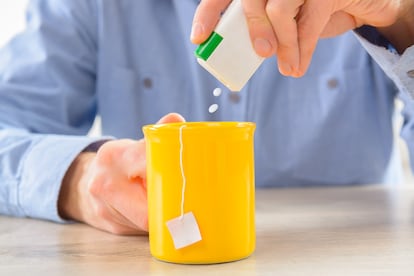 Un hombre echa sacarina en una infusión.