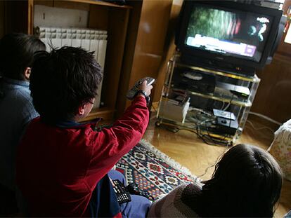 Un grupo de niños ve la televisión en el salón de su casa.