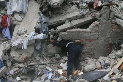 Un treballador busca víctimes entre la runa d'un edifici esfondrat després del terratrèmol.