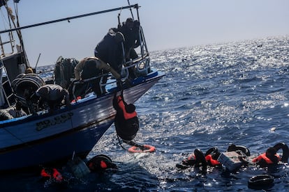 Un migrante es subido a bordo de un pesquero que ha participado también en las labores de rescate.