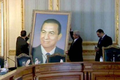 Funcionarios descuelgan un retrato de Mubarak de las paredes de un edificio gubernamental.