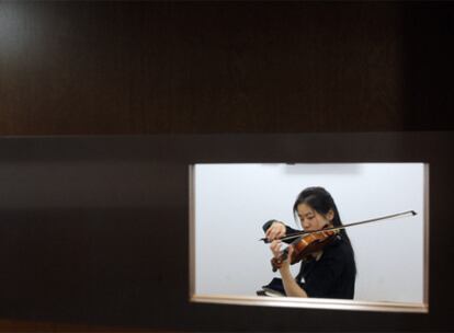 Una alumna de la Escuela Superior de Música Reina Sofía practica en una sala de ensayo. En la puerta, una pantalla indica quién y cuánto tiempo ocupa la cabina.