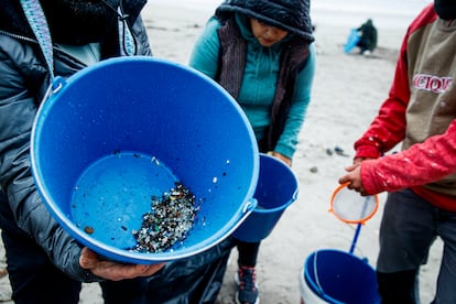 Varias personas recogen este martes los pellets de plástico acumulados en la playa de Patos, en Nigrán (A Coruña). 