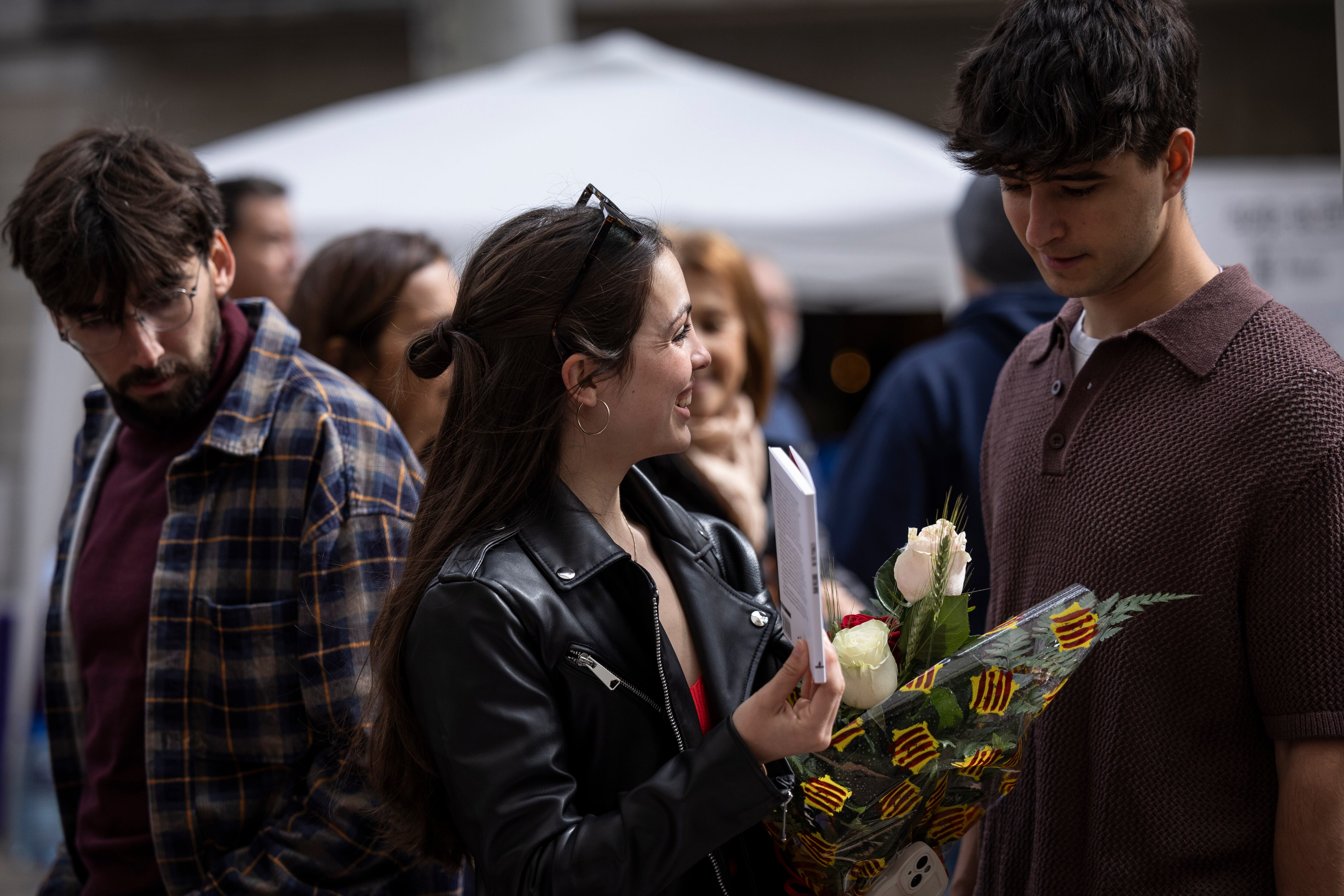 Una joven con un ramo de rosas mira libros en la Rambla, este martes en Barcelona.