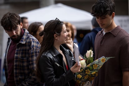 Una joven con un ramo de rosas mira libros en la Rambla, este martes en Barcelona.


