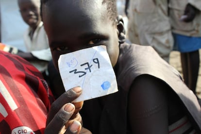 Un chico sujeta su número de registro mientras sigue la ceremonia en la que se formaliza su liberación por parte de la Facción Cobra, en Lekuangole, en el Estado de Jonglei (Sudán del Sur).