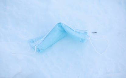 Una mascarilla tirada en el suelo sobre la nieve.