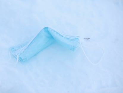 Una mascarilla tirada en el suelo sobre la nieve.