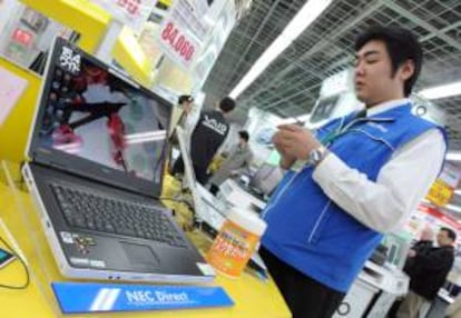 Un empleado limpia un ordenador NEC en una tienda de Tokio (Japón). EFE/Archivo