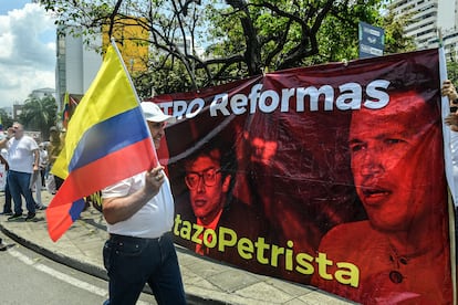 Un manifestante marcha junto a una manta con las imágenes de Gustavo Petro y el expresidente venezolano Hugo Chávez, en Cali. 