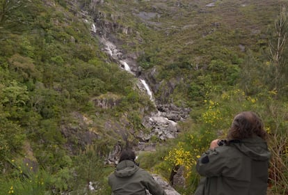Dos personas observan la bajada escalonada del agua del río Fecha, que forma grandes saltos en su descenso.