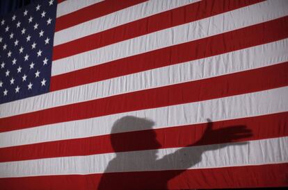 La sombra de Rick Perry se proyecta sobre una bandera de EE UU durante el acto celebrado en Boone, Iowa, primera parada de las primarias republicanas.
