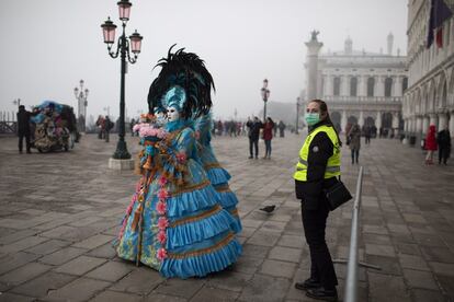 Las autoridades italianas han cancelado los dos últimos días del Carnaval de Venecia debido al brote de coronavirus que ya ha causado varias víctimas mortales. En la imagen, un miembro de seguridad, protegida con una mascarilla, en Venecia, el 23 de febrero.