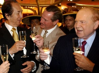 Ho (corbata dorada) y Adelson (corbata morada) brindan tras la apertura de un casino del segundo en Macao en 2004.