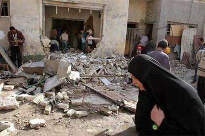 Una mujer pasa delante de los restos de una casa en Bagdad tras la explosión ayer de una bomba.