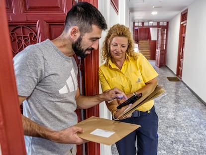 La cartera Ángeles Nava le entrega la documentación del voto por correo a Carlos González en el barrio de La Latina de Madrid.