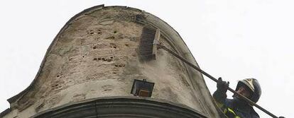 Un bombero limpia la cúpula del edificio del que se ha desprendido el escudo.