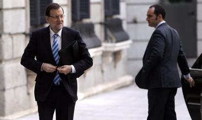 El presidente del Gobierno, Mariano Rajoy, se abrocha la chaqueta de su traje al bajar del coche en la entrada al Congreso de los Diputados.